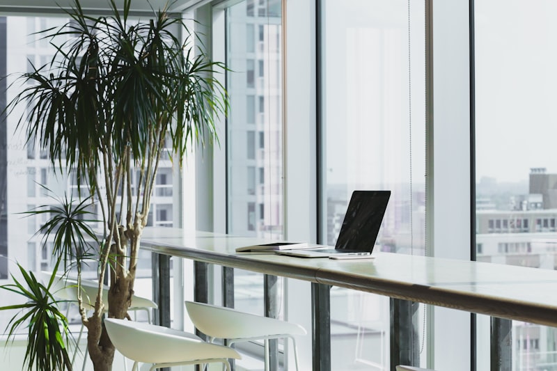 A clean, modern desk with a laptop displaying code, a coffee cup, and a notebook in a brightly lit room. High quality, realistic DSLR photography. No humans in frame.